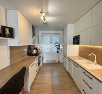 A kitchen in a 3-room apartment with a wooden decor floor and white cabinets.