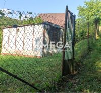 A gate plot in the gardens of Humenné, surrounded by lush greenery and hills.