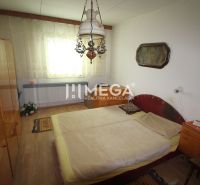 Bedroom in a family house with a chandelier, bed, and wooden decor flooring.