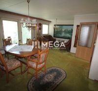 Dining room in a family house with a wooden table and chairs, green carpet, chandeliers.