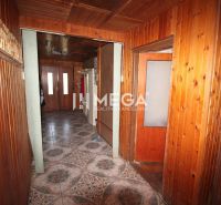 A hallway in a family house with wooden paneling and patterned tiles.