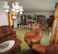 A living room in a family house with a leather sofa, wooden furniture, and a decorative chandelier.