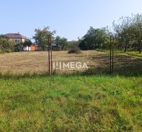 Building plot for sale in Humenné, fenced with a wire fence, house in the background.