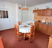 A kitchen in a family house with wooden decor cabinets and a round table.