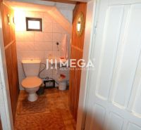 A toilet with tiles and a small window in a family house.