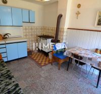 A kitchen in a family house with an old tiled stove and blue kitchen cabinets.