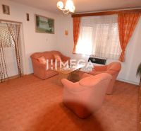 Living room in a family house with orange furniture and carpet, curtains on the windows.