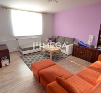 Living room in a family house with sofas, wooden decor, and a shelf.