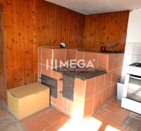 A traditional kitchen with a tiled stove and cooker in a family house has wooden paneling.