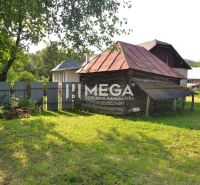 A wooden house in the village of Vyšné Ladičkovce, surrounded by greenery and fencing.