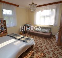 Room with a bed, bookshelf, and soft carpet in a family house.