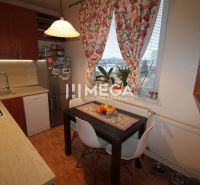 A kitchen in a 3-room apartment with a table, floral curtains, and a floor with a wooden decor.