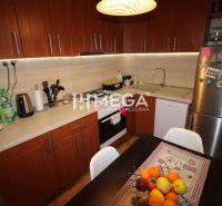 A kitchen in a 3-room apartment, with wooden cabinets and fruit on the table.