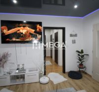 Living room in a three-room apartment with a wooden decor floor and a television.