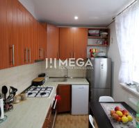 A kitchen in a 3-room apartment with a wooden decor floor and a spacious window.