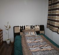 Bedroom in a 3-room apartment with a bed, wood-patterned flooring, and striped curtains.