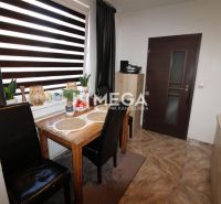 Dining area with a wooden table and black chairs in a 3-room apartment.