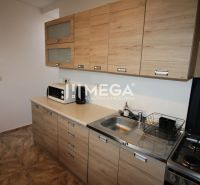 A kitchen in a 3-room apartment with a wooden decor floor and light cabinets.