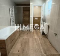 A bathroom with a bathtub, shower, and floor with a wooden decor in a 4-room apartment.