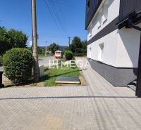 The exterior of a 4-room apartment in Jasenov with a road and a bus, surrounded by greenery.