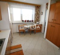 A kitchen in a family house with ceramic tiles and wooden cabinets.