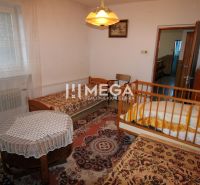 A room with beds and a crib in a family house, decorated with curtains and carpets.