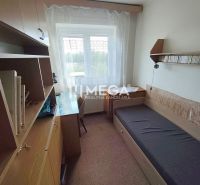A room in a family house with a bed, a table, and bookshelves.