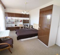 Bedroom in a family house with a bed, cabinets, and an armchair, decorations on the shelves.