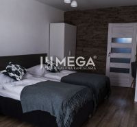 Interior of a room with two beds, a wall with stone decor, flooring with wooden decor.