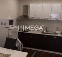 A kitchen with a microwave, refrigerator, and sink, wood-patterned flooring in hotel premises.
