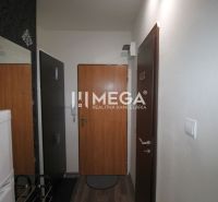 A hallway in a recreational apartment with a wooden decor floor, wallpaper, and a refrigerator.