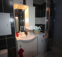 Bathroom in a holiday apartment with a shower, sink, and washing machine.