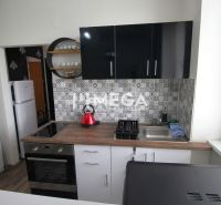 A kitchen in a holiday apartment with a wooden decor floor and geometric tiles on the wall.