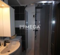 Bathroom in a holiday apartment with a sink, shower, and mirror with lighting.