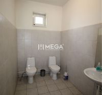 Office restroom with two toilets and a sink, tiled with white tiles.