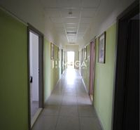 A hallway in offices with pale walls and light tiled flooring.