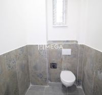 A bathroom in commercial premises with a simple design, featuring a toilet and a narrow window.
