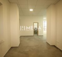 Commercial space with tiles, white walls, and a window, appears spacious and bright.