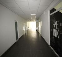 A long corridor in an office with a dark floor and a white ceiling.