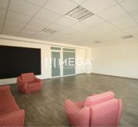An office with four chairs, a wooden floor, and a large board.