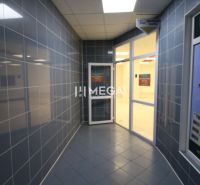 A corridor with a tiled floor and glass doors in commercial premises.