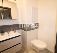 A bathroom in a 2-room apartment with a sink, mirror, and toilet.