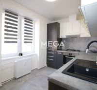 A kitchen in a 2-room apartment with practical equipment and gray floor tiles.
