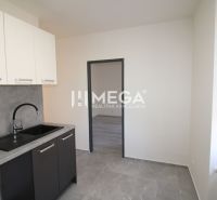 A kitchen with a black sink and white cabinets in a 2-room apartment.