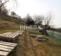 Gardens in Humenné at ZO Poniklec, a grassy slope with pallets and a wooden gazebo.