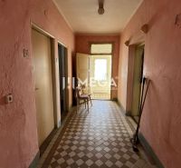 The interior of a family house with tiles, pink walls, and old furniture.