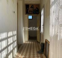 A hallway in a family house with colorful tiles and a curtain, a painting hangs on the wall.