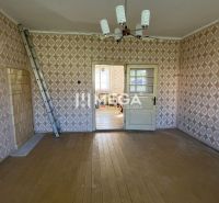 A room in a family house with a wooden decor floor and patterned wallpaper.
