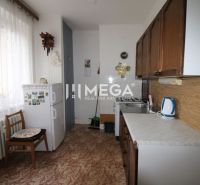 Kitchen in a 2-room apartment with a refrigerator, wooden decor flooring, light curtain.
