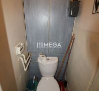 A toilet with a wooden decor in a 2-room apartment with basic amenities.